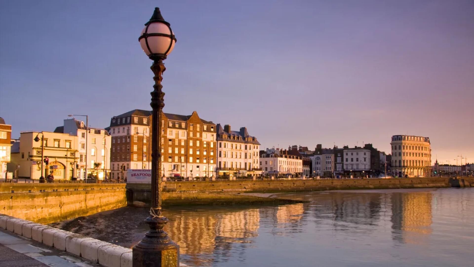 A waterfront view with buildings and a lamp post.