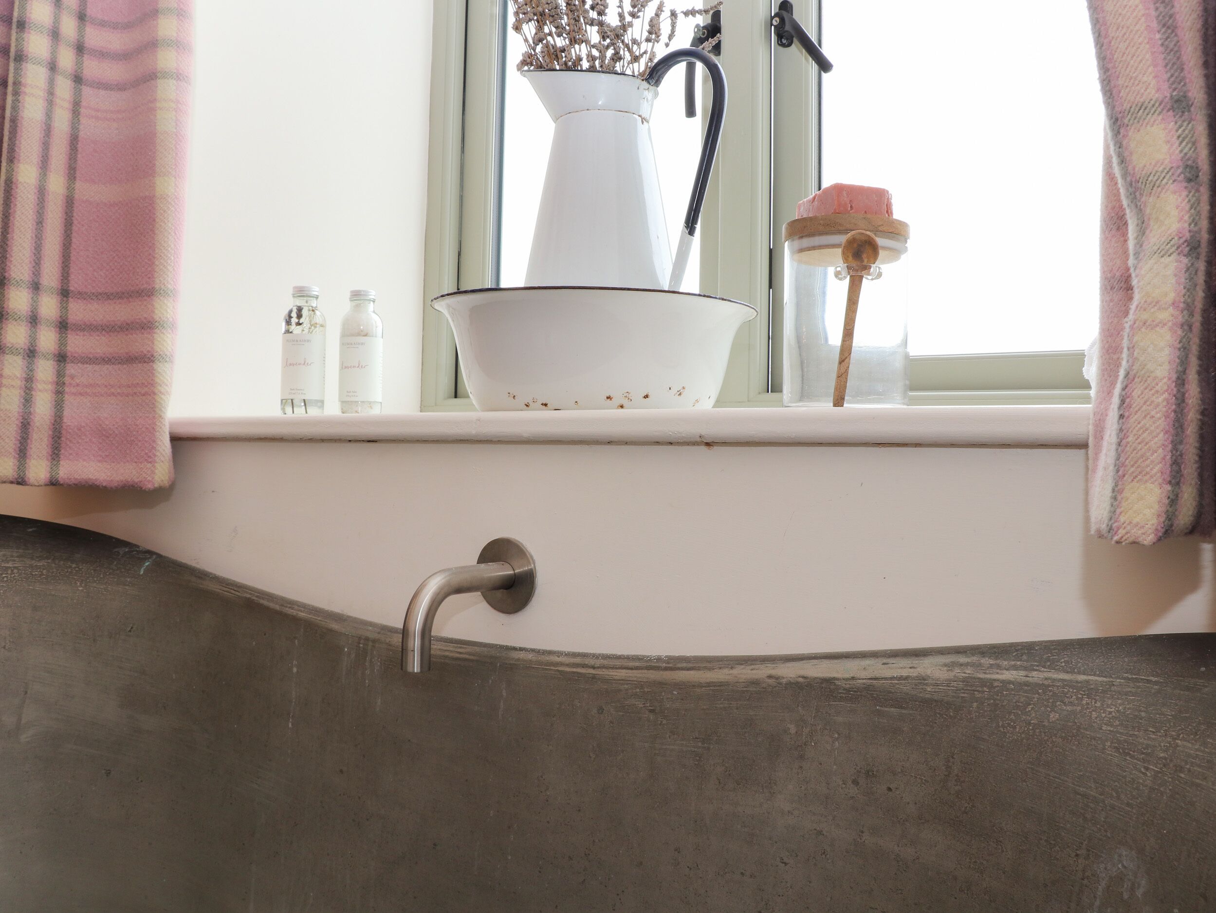 Un lavabo de salle de bain avec un bac blanc, un robinet et une fenêtre au-dessus.