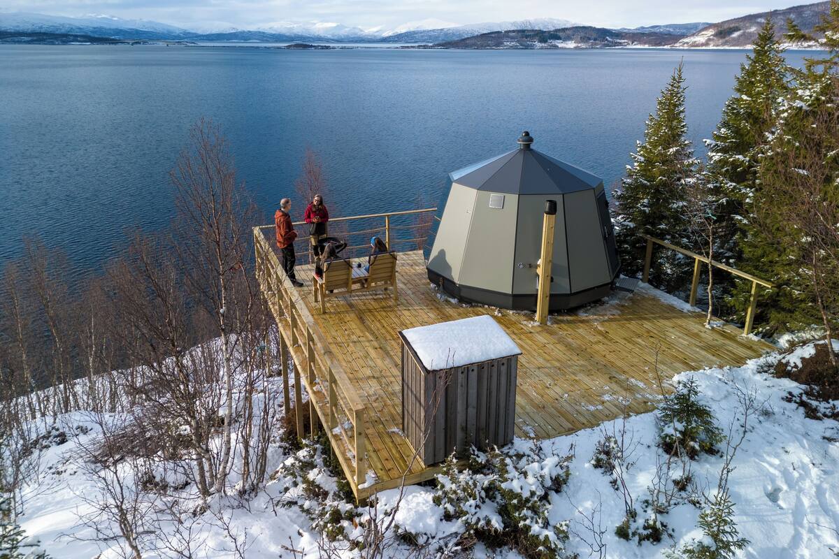 A wooden deck with a gazebo overlooking a lake, surrounded by snow-covered trees.