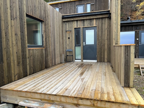 Una terraza de madera con una puerta corrediza y una ventana.