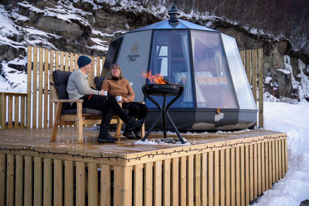 A wooden deck with a glass igloo-style structure labeled "Aurora Hut" and a fire pit.