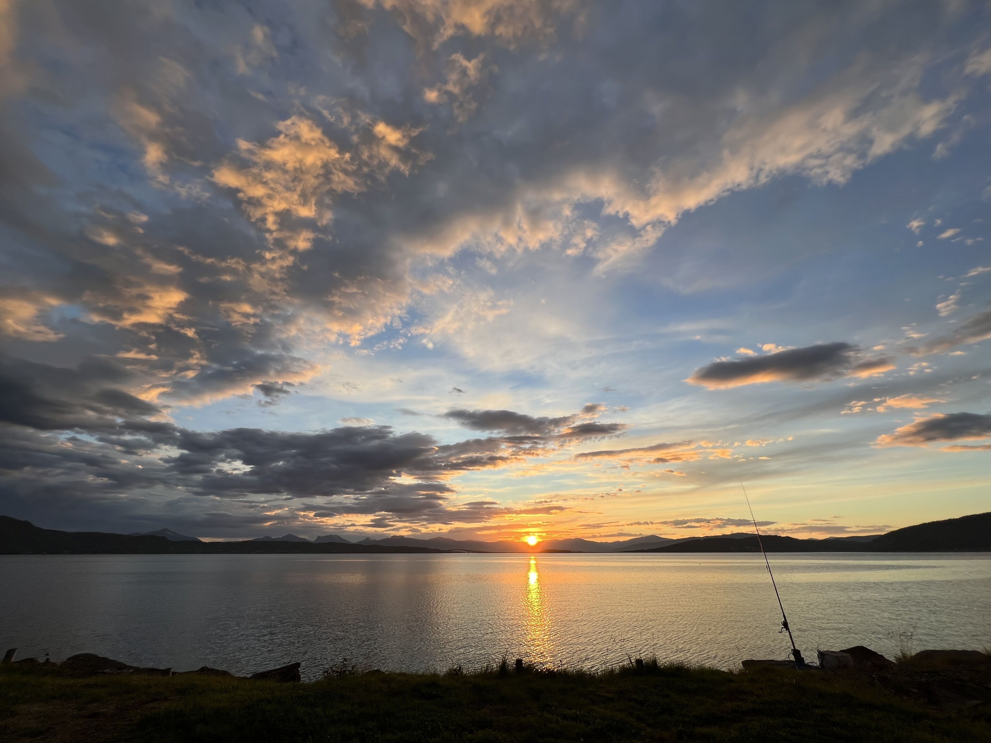 Tyyni järvi auringonlaskun aikaan, etualalla on kalastusvapa.
