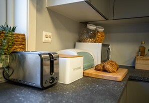 En köksbänk med en brödrost, en brödlåda, en skärbräda med bröd och burkar med kryddor.
