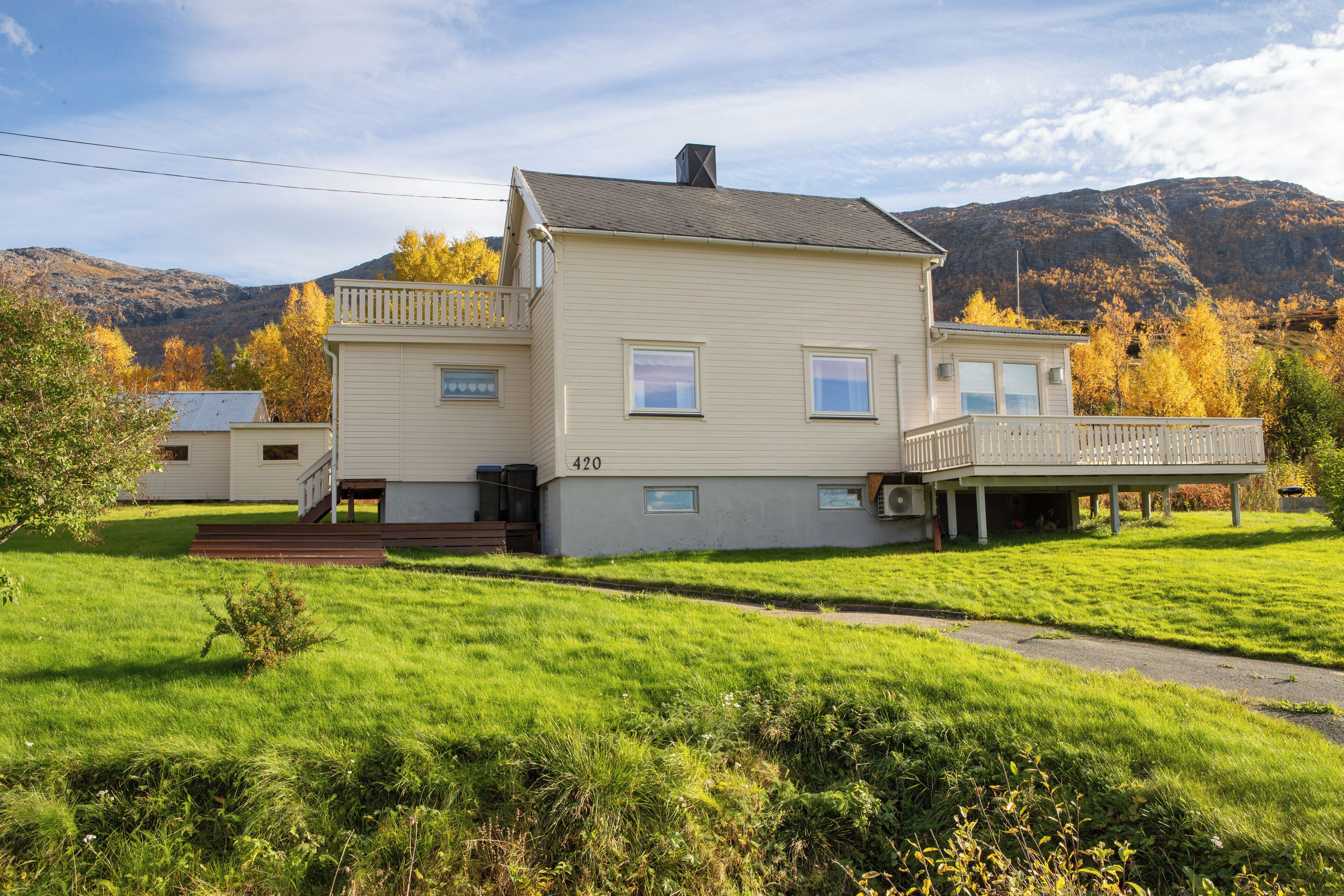 A two-story house with a balcony, a number '420' on the side, and a grassy yard.