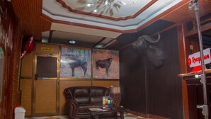 Un área de recepción con un sofá de cuero, una mesa de centro, un televisor montado en la pared y una estatua de toro.