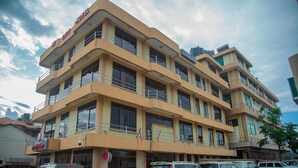 Un hotel de varios pisos con balcones, estacionamiento y un letrero que indica un restaurante.