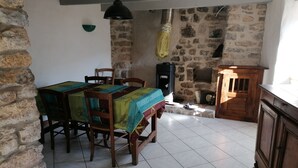 Un área de comedor con una pared de piedra, un calentador negro y un armario de madera.
