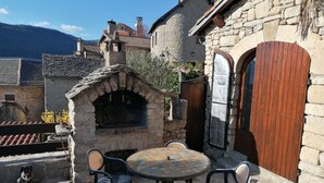 Un edificio de piedra con puerta de madera y un pequeño espacio al aire libre con una mesa redonda y sillas.