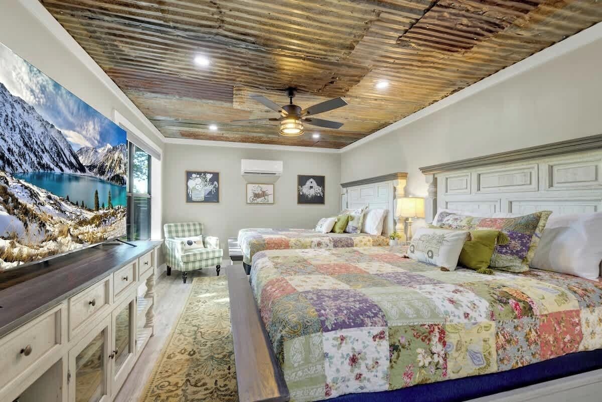 Un dormitorio con una cama grande, un ventilador de techo y un mural de un lago de montaña.
