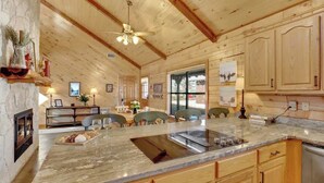 A wooden interior with a kitchen island, dining area, and a fireplace.