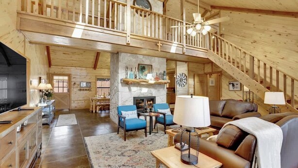 A spacious living area with a fireplace, wooden furniture, and a staircase connecting to an upper level.