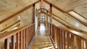 A wooden interior with a central staircase, stone walls, and a skylight.