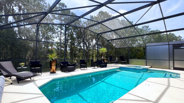 A covered outdoor swimming pool with lounge chairs and potted plants. - Private Pool Oasis! No Rear Neighbors! VALUE RATE! (Davenport)