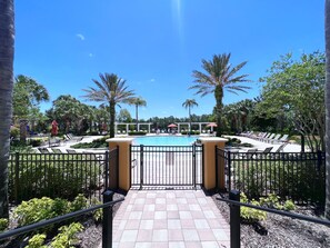 Un espace piscine avec des chaises longues et une entrée fermée par un portail.