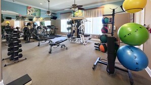 Un gimnasio con diversos equipos de ejercicio, incluyendo cintas de correr, máquinas de pesas y pelotas de ejercicios.