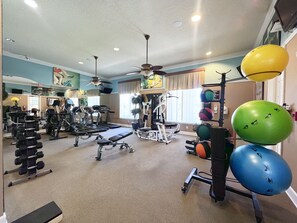 Une salle de sport équipée de divers appareils d’exercice, notamment des tapis de course, des appareils de musculation et des ballons d’exercice.