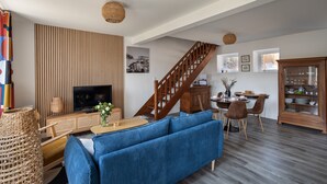 Un salon moderne avec un téléviseur, un canapé et un coin repas.