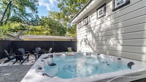 A hot tub in a backyard with a wooden fence, chairs, and a house in the background. - Southern Charm - Near Main With Hot Tub (Fredericksburg)
