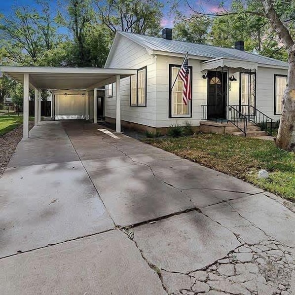 Una casa a un piano con un portico coperto, un ingresso con gradini e un vialetto.