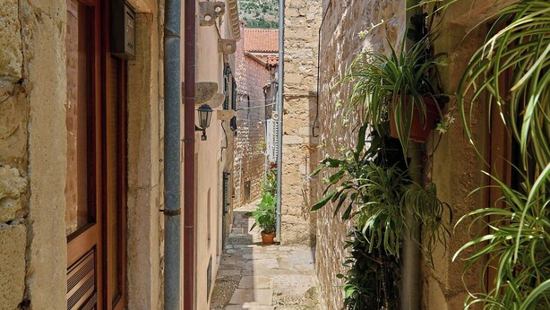 A narrow cobblestone alley with stone buildings, potted plants, and a clear blue sky. - Hedera Estate, Hedera A6 (Dubrovnik)
