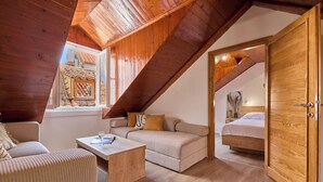 A cozy attic bedroom with a sloped ceiling, wooden beams, a sofa, a small table, and a bed. - Hedera Estate, Hedera A6 (Dubrovnik)
