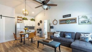 A spacious living area with a dining table, sofa, and ceiling fan.