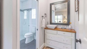 A bathroom with a white vanity, a large mirror, and a glass shower enclosure.