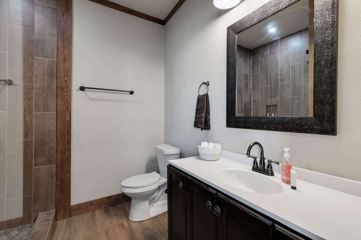 A modern bathroom with a white sink, black faucet, and a large mirror.