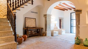 A staircase with a wooden railing, a stone wall, and a rustic wooden table with pottery. - Agroturisme Subies (Selva)