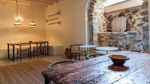 A rustic dining area with a stone wall, wooden furniture, and hanging light fixtures. - Agroturisme Subies (Selva)