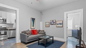 Een moderne woonkamer met een grijze bank, een salontafel en kunst aan de muur.