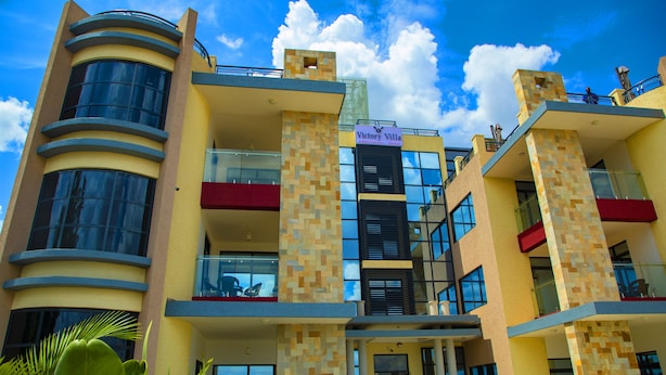 Um hotel de vários andares com design moderno, apresentando varandas, grandes janelas e uma placa chamativa para "Victory Villa".