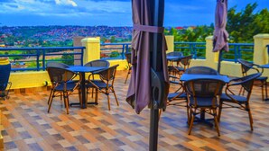 Terraço com área de estar ao ar livre e vista para uma cidade distante.