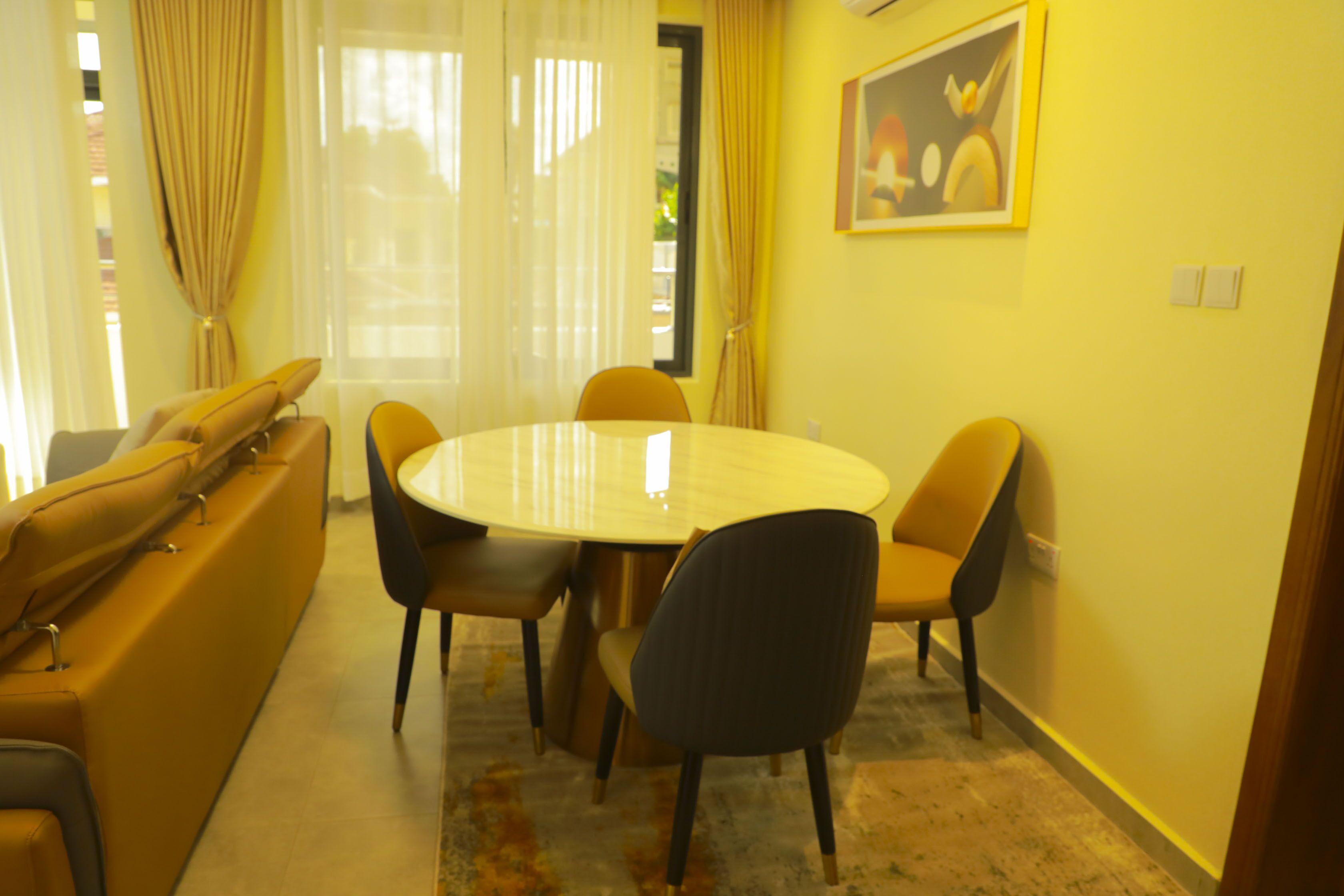 Un coin repas avec une table ronde et six chaises, un canapé et un tableau au mur.