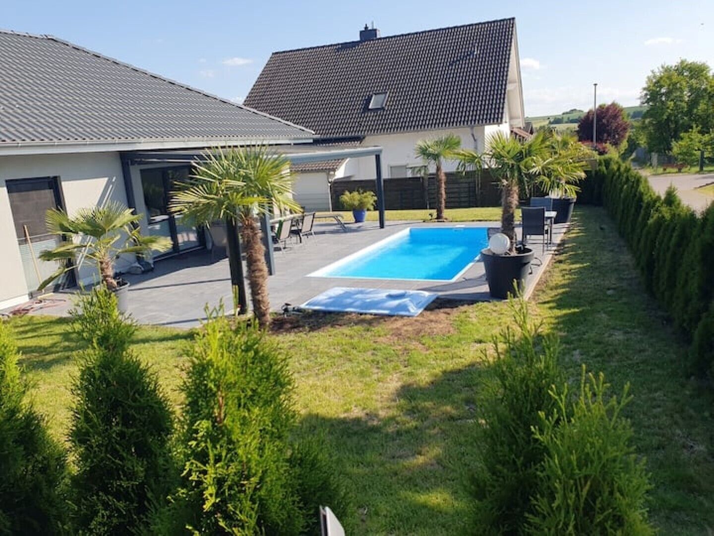 Propiedad residencial con piscina, terraza techada y césped bien cuidado.