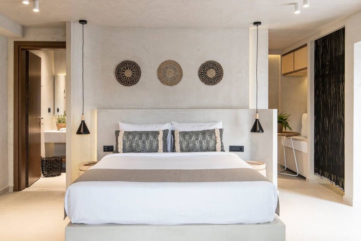 Une chambre à coucher moderne avec un grand lit, des tables de chevet et des œuvres d’art décoratives au mur.