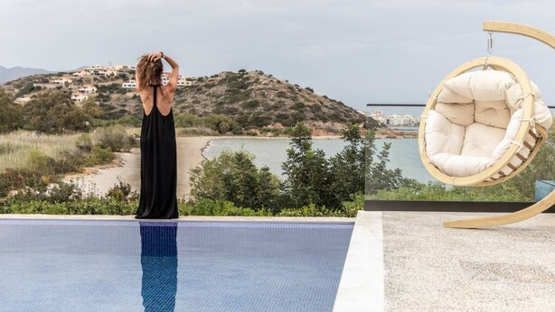 Eine Person steht am Pool mit Blick auf eine Hügelkuppe und einen Hängestuhl.