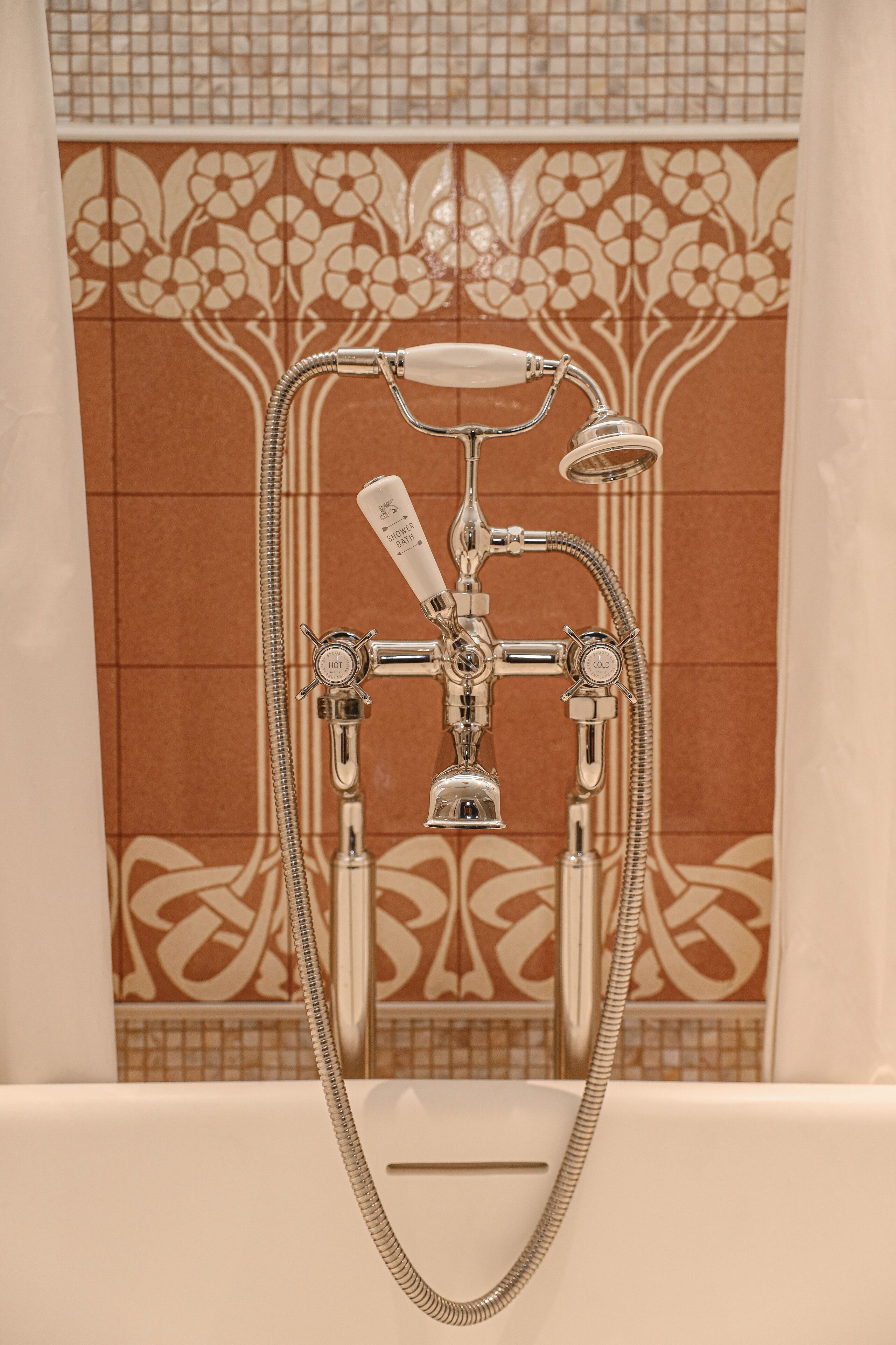 A bathroom with a shower and bathtub, featuring a decorative tile backsplash and a chrome showerhead.