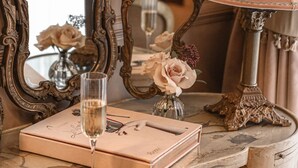 Una mesa de estilo vintage con una copa de champán, una caja decorativa y un jarrón con flores.