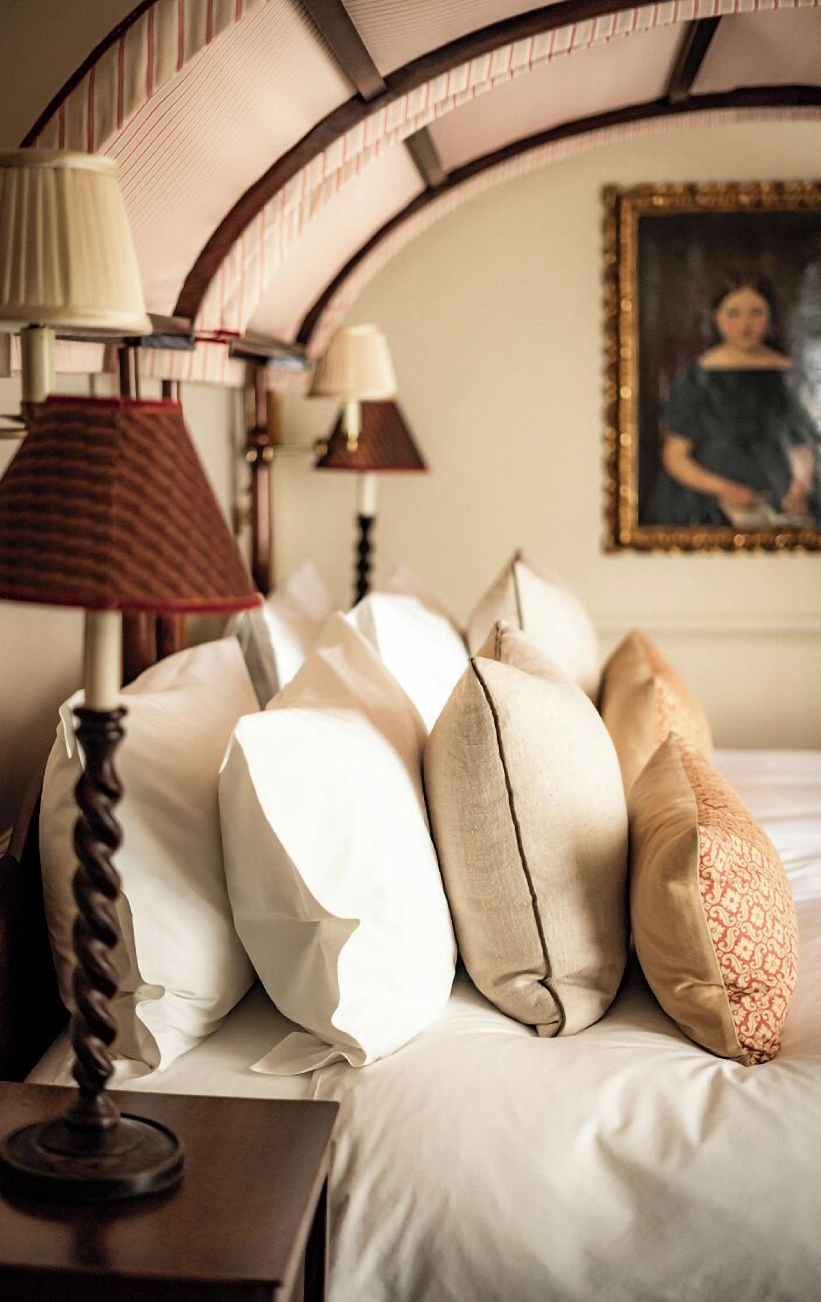 A neatly made bed with multiple pillows and a lamp on a bedside table.