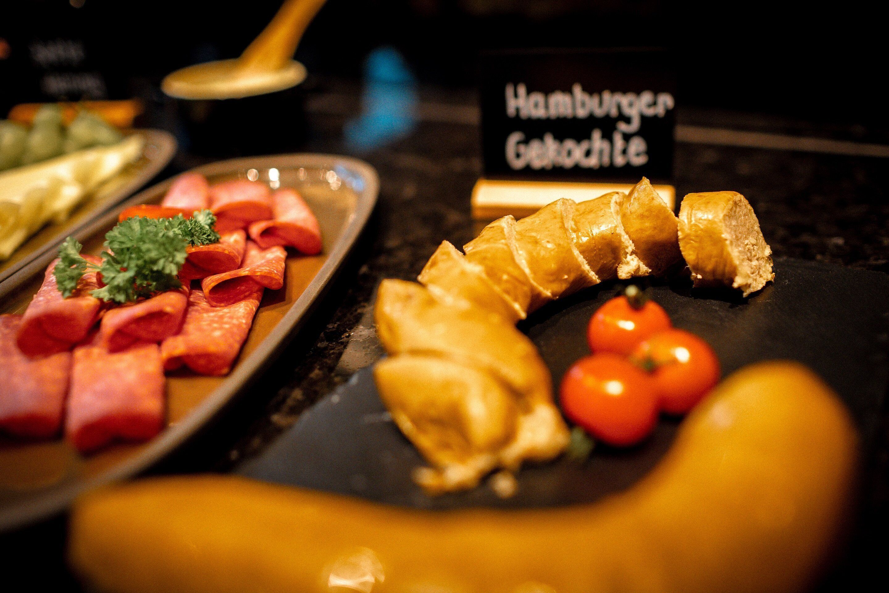 Ein Buffet mit verschiedenen Speisen, darunter Aufschnitt, Gebäck und Tomaten.