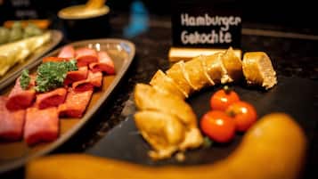 Ein Buffet mit verschiedenen Speisen, darunter Aufschnitt, Gebäck und Tomaten.