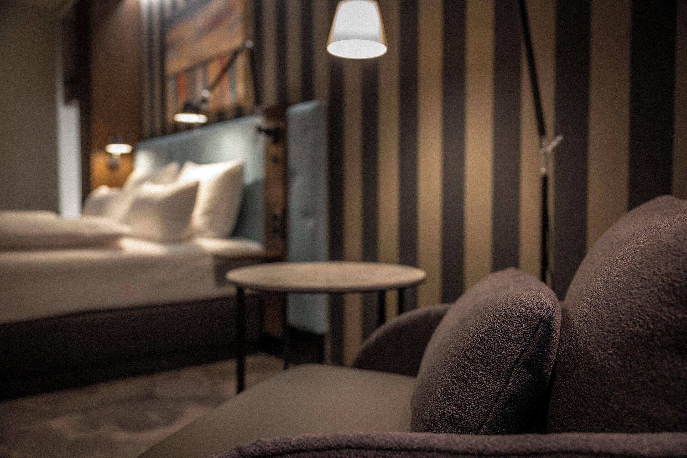 A hotel room with a bed, a round table, and a lamp.