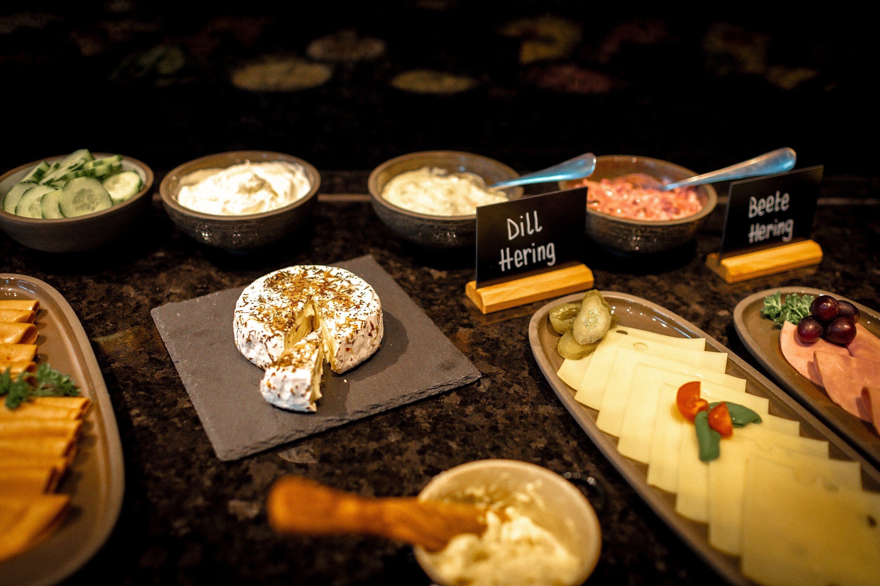 A buffet with various food items including cheese, meats, and dips.