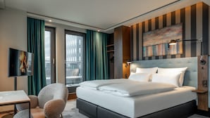 A modern hotel room with a large bed, a desk, and a chair.