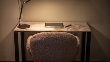Un escritorio con una lámpara, una computadora portátil y un bolígrafo.