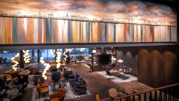 A modern lounge area with seating arrangements and a large, colorful mural depicting a city skyline.