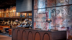 A modern bar area with a counter, pendant lighting, and a mural with text.