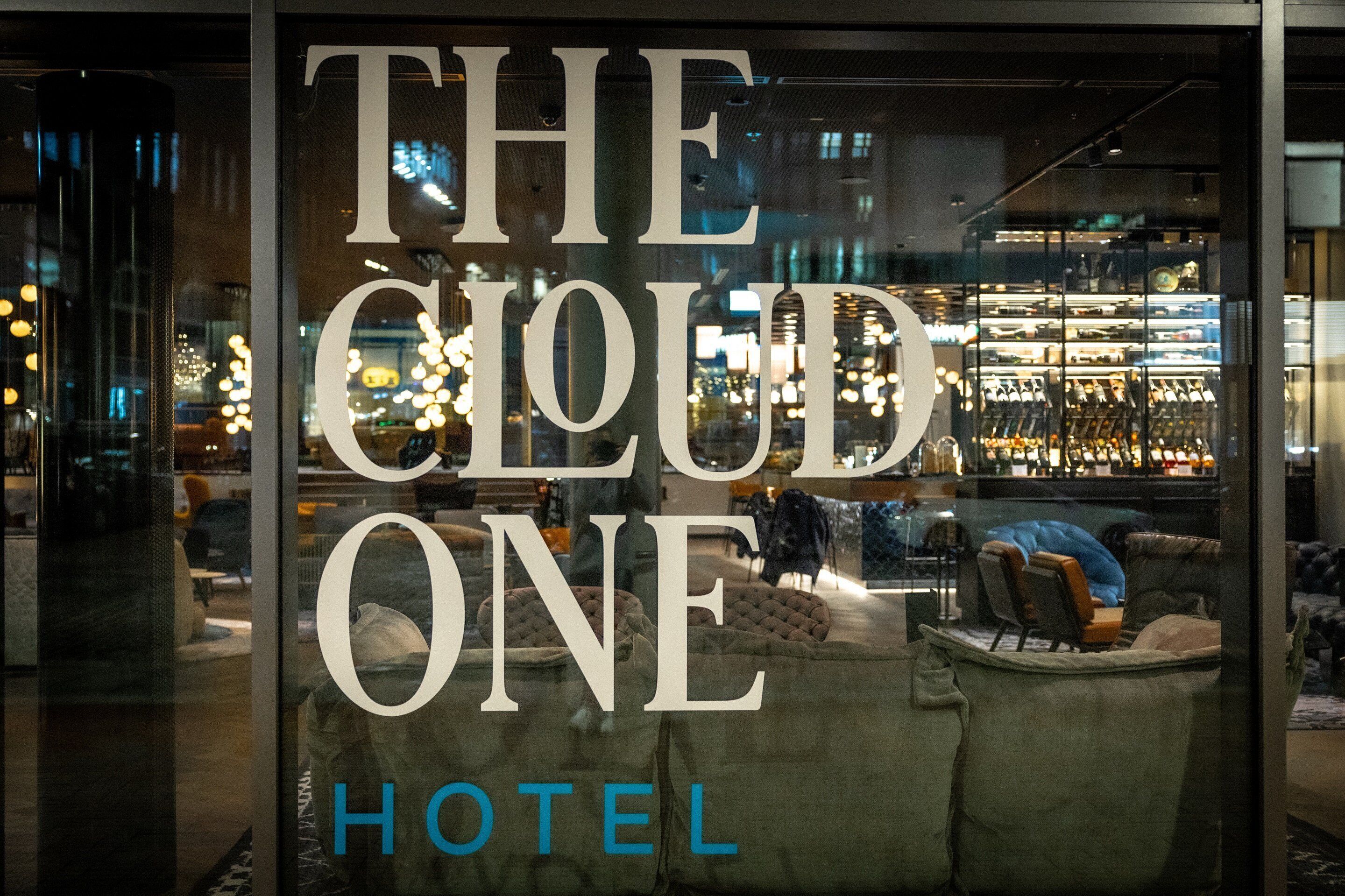 A hotel interior with a large window displaying the name "THE CLOUD ONE HOTEL".