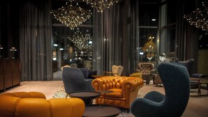 A modern lounge area with leather sofas, a blue armchair, and a patterned rug.